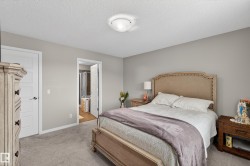 Bedroom with light colored carpet, a textured ceiling, and connected bathroom - 