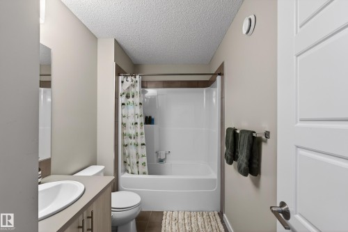 Full bathroom with a textured ceiling, shower / bath combination with curtain, vanity, and dark tile patterned floors - 5910 Anthony Crescent, Edmonton, AB - Indoor Photo Showing Bathroom