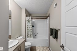Full bathroom with a textured ceiling, shower / bath combination with curtain, vanity, and dark tile patterned floors - 