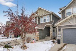 Craftsman house featuring a garage, stone siding, and roof with shingles - 