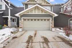 Craftsman-style house featuring board and batten siding, stone siding, concrete driveway, and a garage - 