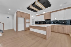 Kitchen with decorative light fixtures, tasteful backsplash, light wood-type flooring, dual tone cabinets, and a center island with sink - 