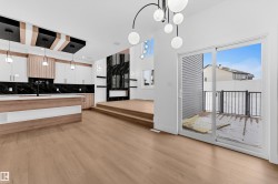 Kitchen featuring backsplash, decorative light fixtures, modern cabinets, light wood finished floors, and dual tone cabinetry - 