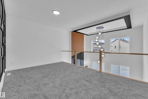 Empty room with carpet flooring and hanging lights - 733 Astoria Way, Devon, AB - Indoor Photo Showing Other Room