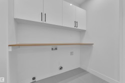 Laundry area featuring hookup for a washing machine, cabinet space, and light tile patterned floors - 