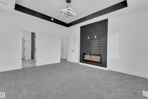 Unfurnished living room with carpet, a fireplace, and a wooden tray ceiling - 733 Astoria Way, Devon, AB - Indoor Photo Showing Other Room