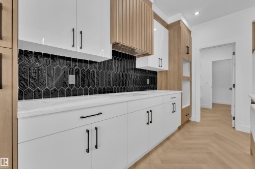 Kitchen with parquet floors, white cabinets, recessed lighting, tasteful backsplash, and light stone countertops - 737 Astoria Way, Devon, AB - Indoor