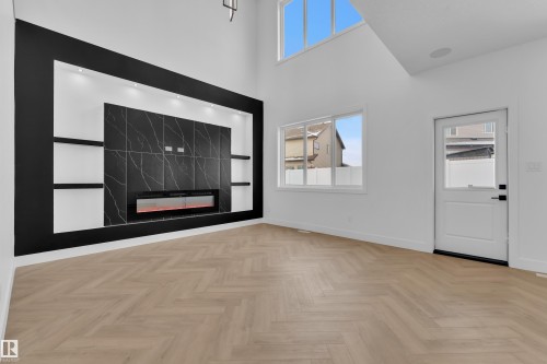 Spare room featuring a high end fireplace, a high ceiling, healthy amount of natural light, and parquet flooring - 737 Astoria Way, Devon, AB - Indoor Photo Showing Other Room