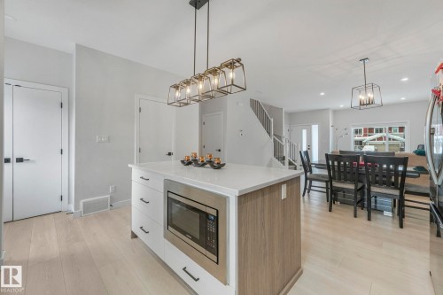 Kitchen with modern cabinets, a center island, stainless steel appliances, light wood finished floors, and light stone countertops - 21 Sienna Boulevard, Fort Saskatchewan, AB - Indoor