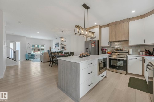Kitchen featuring stainless steel appliances, pendant lighting, a center island, light wood-style floors, and modern cabinets - 21 Sienna Boulevard, Fort Saskatchewan, AB - Indoor Photo Showing Kitchen