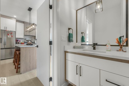 Bathroom featuring vanity, decorative backsplash, and light wood-type flooring - 21 Sienna Boulevard, Fort Saskatchewan, AB - Indoor Photo Showing Bathroom