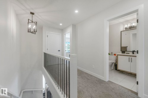 Corridor with light carpet, hanging lights, and an upstairs landing - 21 Sienna Boulevard, Fort Saskatchewan, AB - Indoor Photo Showing Other Room
