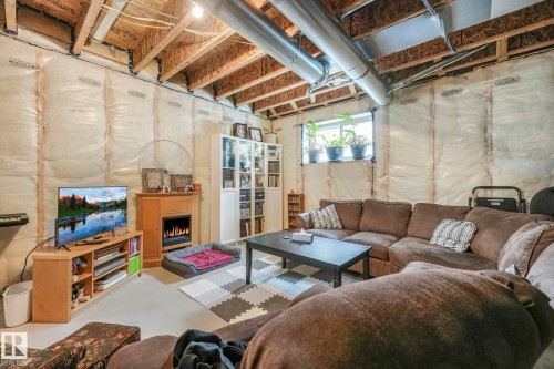 Living room featuring a lit fireplace and concrete flooring - 21 Sienna Boulevard, Fort Saskatchewan, AB - Indoor Photo Showing Basement
