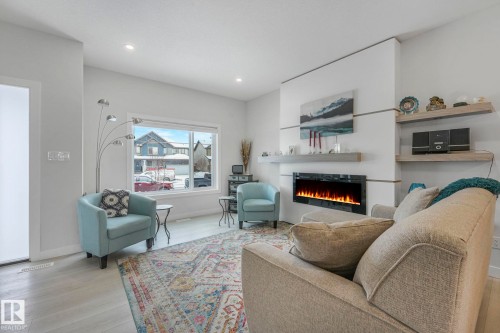 Living room with light wood-type flooring, a warm lit fireplace, and recessed lighting - 21 Sienna Boulevard, Fort Saskatchewan, AB - Indoor Photo Showing Living Room With Fireplace