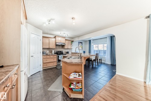Kitchen with an island with sink, light countertops, stainless steel electric range, open shelves, and freestanding refrigerator - 5814 165 Avenue, Edmonton, AB - Indoor Photo Showing Kitchen