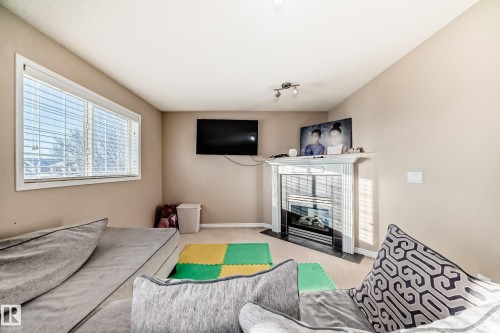 Carpeted living area with baseboards and a fireplace - 5814 165 Avenue, Edmonton, AB - Indoor With Fireplace