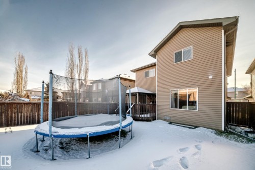 Snow covered house with a trampoline, a deck, and a fenced backyard - 5814 165 Avenue, Edmonton, AB - Outdoor With Deck Patio Veranda With Exterior