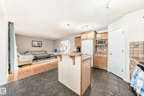 Kitchen featuring arched walkways, light wood finish cabinets, a kitchen bar, light countertops, and freestanding refrigerator - 5814 165 Avenue, Edmonton, AB - Indoor Photo Showing Kitchen