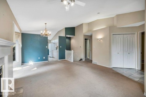Unfurnished living room featuring vaulted ceiling, carpet floors, a fireplace with flush hearth, suspended lighting, and ceiling fan - 112 Haddow Close, Edmonton, AB - Indoor Photo Showing Other Room