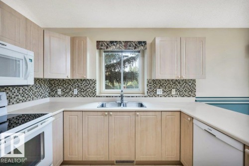 Kitchen with white appliances, light wood finish cabinetry, light countertops, and tasteful backsplash - 112 Haddow Close, Edmonton, AB - Indoor Photo Showing Kitchen With Double Sink