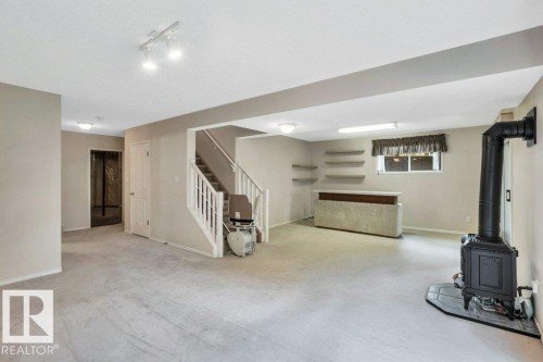 Basement featuring carpet floors, a wood stove, and a textured ceiling - 112 Haddow Close, Edmonton, AB - Indoor Photo Showing Basement
