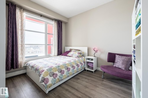 Bedroom featuring wood finished floors and a baseboard heating unit - 407 2590 Anderson Way, Edmonton, AB - Indoor Photo Showing Bedroom