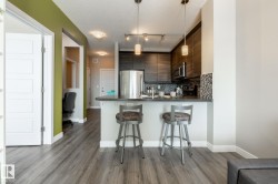 Kitchen featuring dark countertops, a textured ceiling, a peninsula, stainless steel appliances, and a breakfast bar area - 