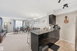Kitchen with a peninsula, a breakfast bar, appliances with stainless steel finishes, pendant lighting, and a textured ceiling - 