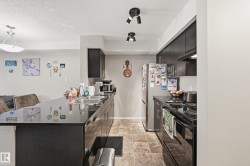 Kitchen featuring dark cabinetry, stainless steel appliances, a kitchen breakfast bar, a peninsula, and dark stone counters - 