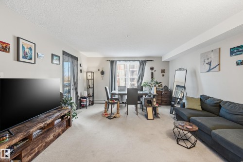 Living area with carpet floors and a textured ceiling - 207 1080 Mcconachie Boulevard, Edmonton, AB - Indoor Photo Showing Living Room
