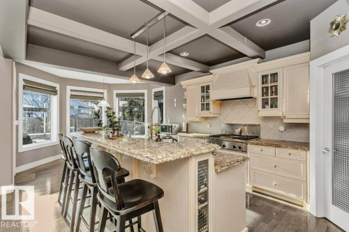 Kitchen with glass insert cabinets, light stone countertops, pendant lighting, tasteful backsplash, and coffered ceiling - 1579 Hector Road, Edmonton, AB - Indoor