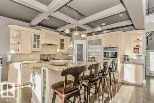 Kitchen with open shelves, coffered ceiling, tasteful backsplash, light stone counters, and hanging light fixtures - 1579 Hector Road, Edmonton, AB - Indoor Photo Showing Kitchen With Upgraded Kitchen