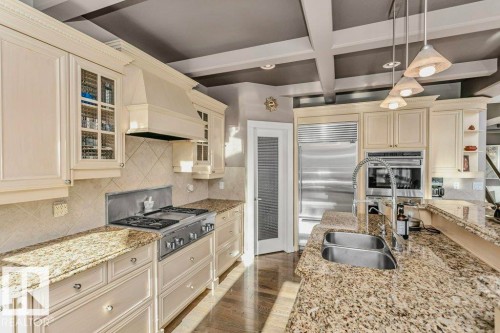 Kitchen with glass insert cabinets, decorative backsplash, light stone countertops, stainless steel appliances, and coffered ceiling - 1579 Hector Road, Edmonton, AB - Indoor Photo Showing Kitchen With Double Sink With Upgraded Kitchen