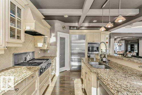 Kitchen featuring cream cabinets, coffered ceiling, stainless steel appliances, light stone counters, and glass fronted cabinets - 1579 Hector Road, Edmonton, AB - Indoor Photo Showing Kitchen With Double Sink With Upgraded Kitchen