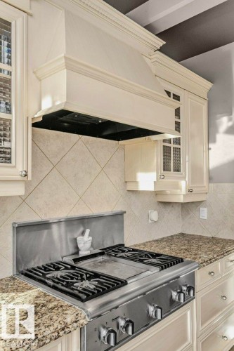 Kitchen featuring glass fronted cabinets, light stone counters, cream cabinets, gas stove, and tasteful backsplash - 1579 Hector Road, Edmonton, AB - Indoor Photo Showing Kitchen With Upgraded Kitchen