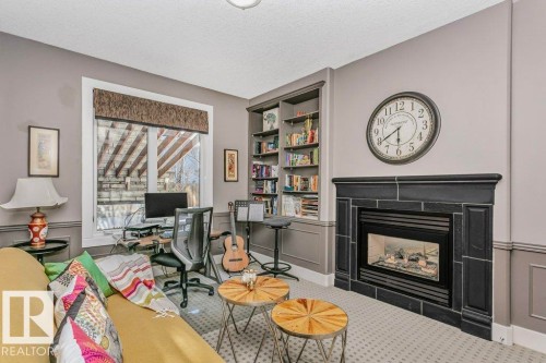 Office area with built in features, a fireplace, a textured ceiling, carpet flooring, and wainscoting - 1579 Hector Road, Edmonton, AB - Indoor Photo Showing Living Room With Fireplace