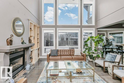 Living area with a high ceiling, a premium fireplace, built in features, and wood finished floors - 1579 Hector Road, Edmonton, AB - Indoor Photo Showing Living Room With Fireplace