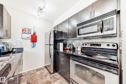 Kitchen featuring stainless steel appliances, backsplash, a textured ceiling, dark countertops, and track lighting - 