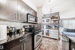 Kitchen featuring stainless steel appliances, track lighting, open shelves, tasteful backsplash, and a textured ceiling - 