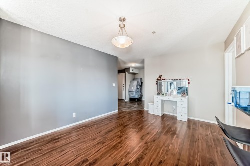 Unfurnished living room with a textured ceiling, dark wood finished floors, and an office area - 302 530 Watt Boulevard Sw, Edmonton, AB - Indoor Photo Showing Other Room