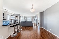 Living room featuring dark wood-style floors, plenty of natural light, and a textured ceiling - 