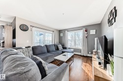 Living room featuring wood-type flooring, plenty of natural light, and baseboard heating - 