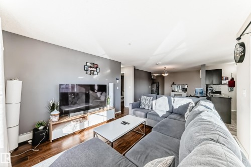 Living room featuring wood finished floors and baseboard heating - 302 530 Watt Boulevard Sw, Edmonton, AB - Indoor Photo Showing Living Room