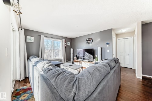 Living room with dark wood-type flooring and baseboards - 302 530 Watt Boulevard Sw, Edmonton, AB - Indoor