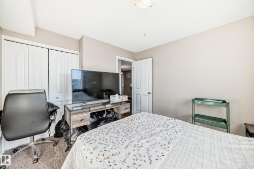 Carpeted bedroom with a closet and a desk - 302 530 Watt Boulevard Sw, Edmonton, AB - Indoor Photo Showing Bedroom