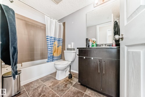 Bathroom featuring vanity, shower / bathtub combination with curtain, and a textured ceiling - 302 530 Watt Boulevard Sw, Edmonton, AB - Indoor Photo Showing Bathroom
