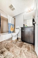 Bathroom with vanity, shower / tub combo, and a textured ceiling - 