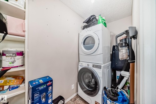 Laundry area featuring stacked washer / dryer and a textured ceiling - 302 530 Watt Boulevard Sw, Edmonton, AB - Indoor Photo Showing Laundry Room