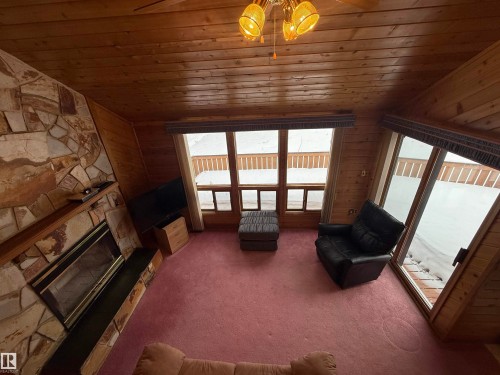 Living room with carpet, a fireplace, wood ceiling, wood walls, and vaulted ceiling - 34 Ella Mae Crescent, Rural Athabasca County, AB - Indoor With Fireplace
