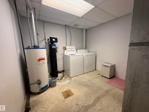 Laundry area featuring concrete flooring, a drop ceiling, separate washer and dryer, and water heater - 34 Ella Mae Crescent, Rural Athabasca County, AB - Indoor Photo Showing Laundry Room